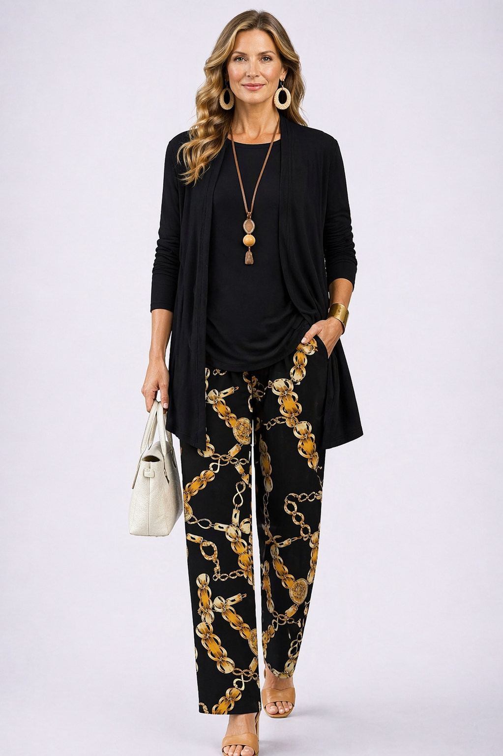 Woman wearing a black and gold three-piece cardigan, top and trousers co-ord set