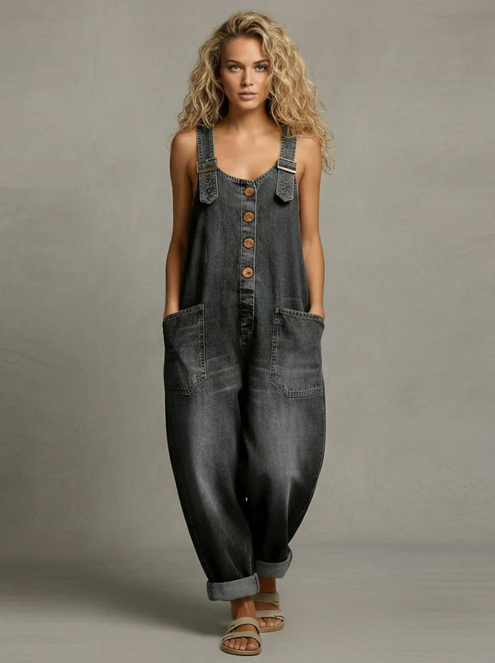 Woman wearing a wide-leg denim jumpsuit with adjustable straps and front pockets