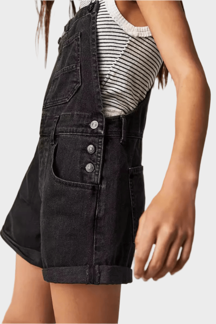 Woman wearing black denim dungaree shorts with adjustable straps
