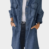 Woman wearing a long denim shirt dress with rolled sleeves and side pockets
