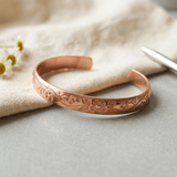Woman wearing a floral engraved copper cuff