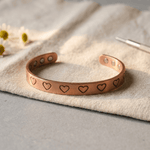 Copper cuff bracelet with a hand-stamped heart pattern