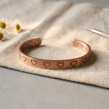 Copper cuff bracelet with a hand-stamped heart pattern